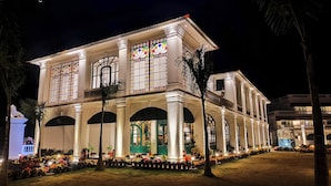 A large, well-lit building with multiple arches and columns, featuring a balcony with a railing. - RESORT TITLI (Bolpur)