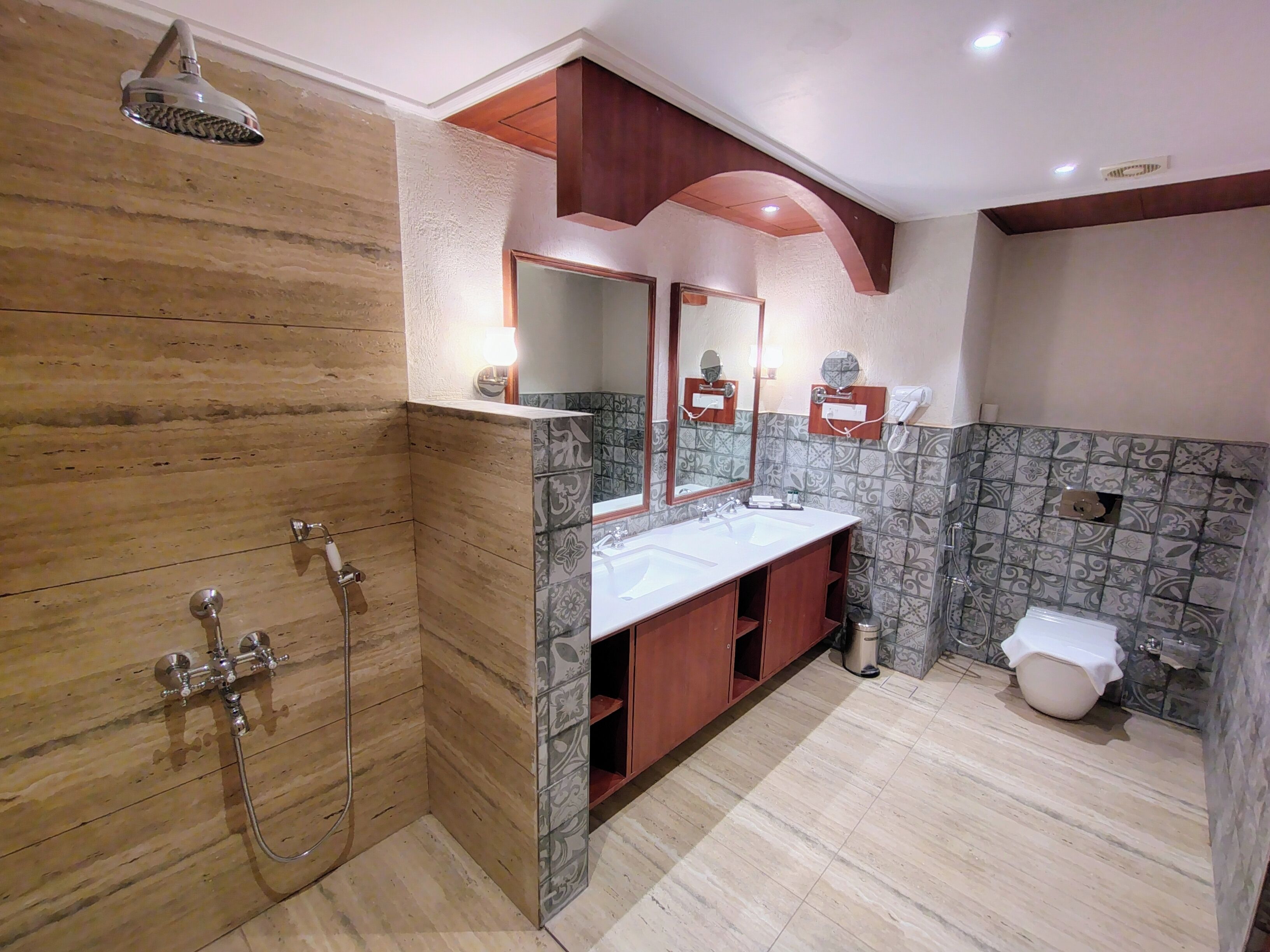 A modern bathroom with a wooden shower enclosure, a vanity with a mirror, and a toilet.