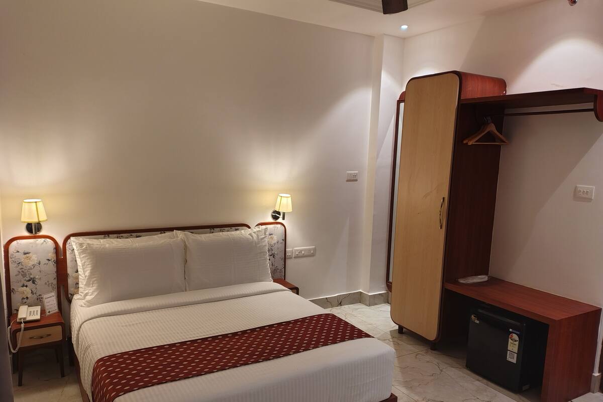 Une chambre d’hôtel comprenant un lit, des lampes de chevet, une armoire et un bureau.