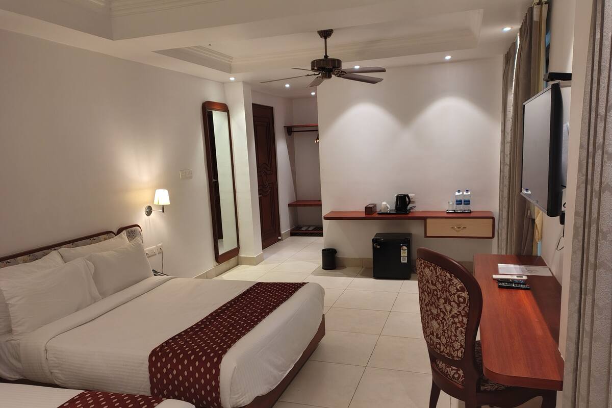 Une chambre d’hôtel équipée d’un lit, d’un bureau, d’une chaise, d’une télévision et d’un ventilateur de plafond.