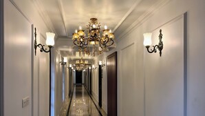 A long, narrow hallway with a reflective floor, ornate chandeliers, and wall sconces. - RESORT TITLI (Bolpur)