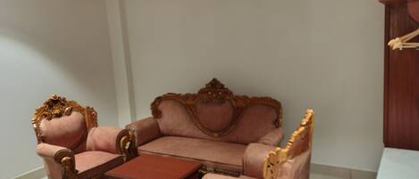 A room with a wooden ceiling fan, a pink sofa set, a wooden coffee table, and a wooden cabinet.