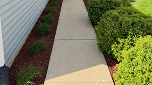 Une maison d’habitation avec une porte d’entrée, un petit porche et un chemin menant à l’entrée.