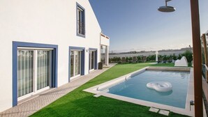 Une maison moderne dotée d’une piscine, d’un patio couvert et offrant une vue sur la mer.