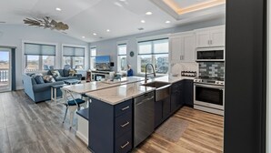 A modern kitchen with a central island, stainless steel appliances, and a dining area with a blue sofa and chairs.