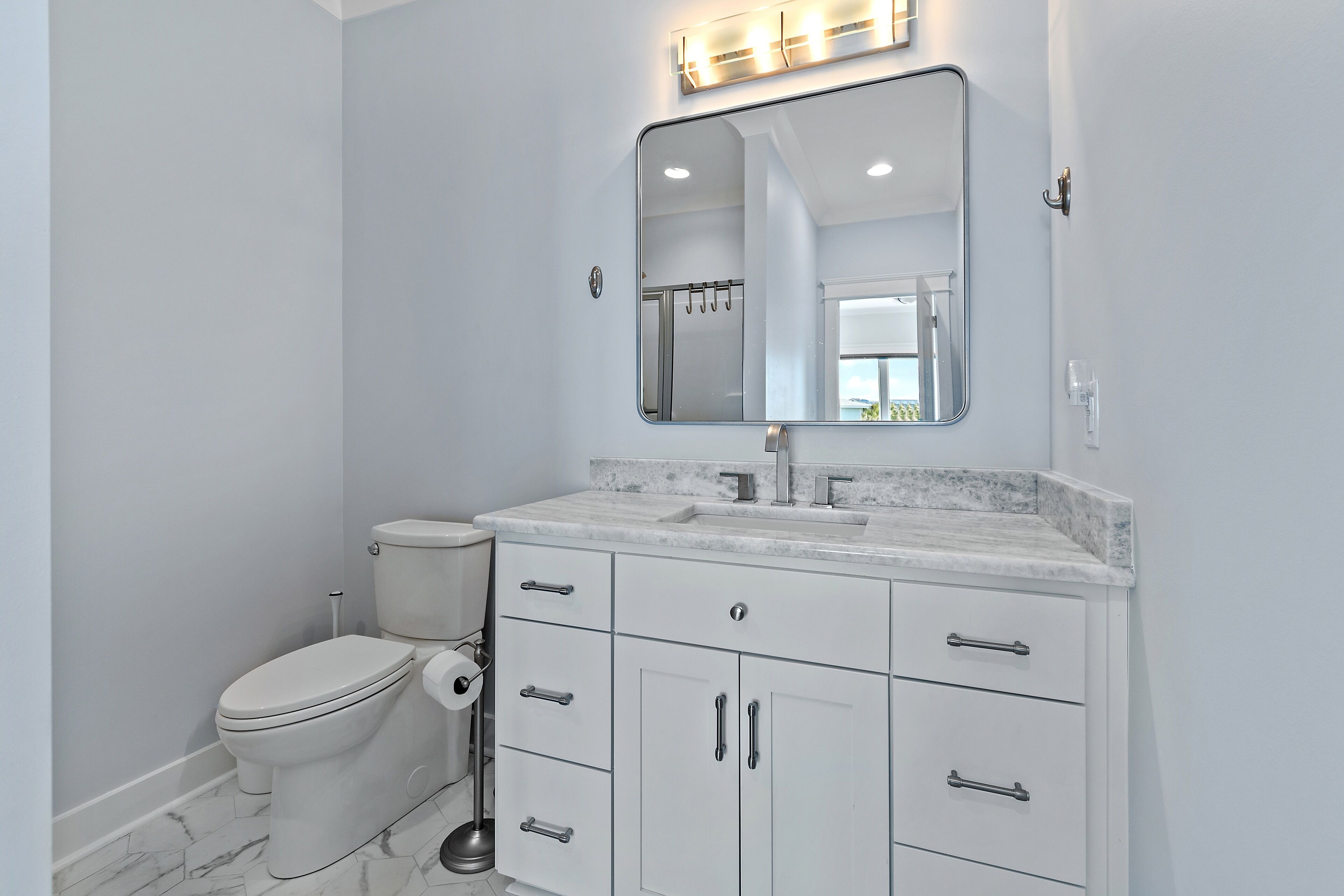 A bathroom with a toilet, a sink, and a mirror.