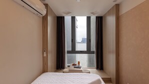Een moderne hotelkamer met een groot bed, uitzicht op het water en een tafeltje met een drankje en een boek.