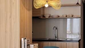 Een moderne keuken met houten kastjes, een spoelbak en een eethoek met twee stoelen.