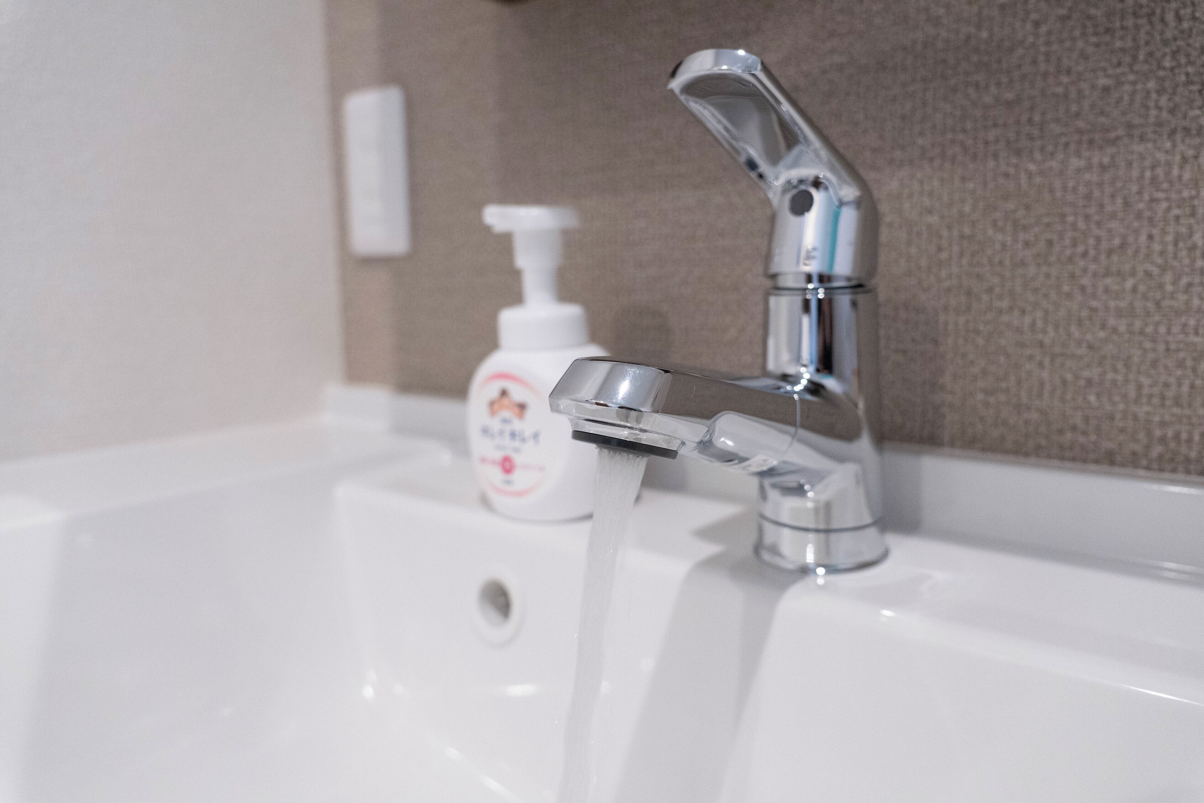 A bathroom sink with a chrome faucet and a soap dispenser.
