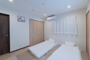 Un dormitorio con dos camas individuales, un armario de madera, aire acondicionado instalado en la pared y un cuadro enmarcado.