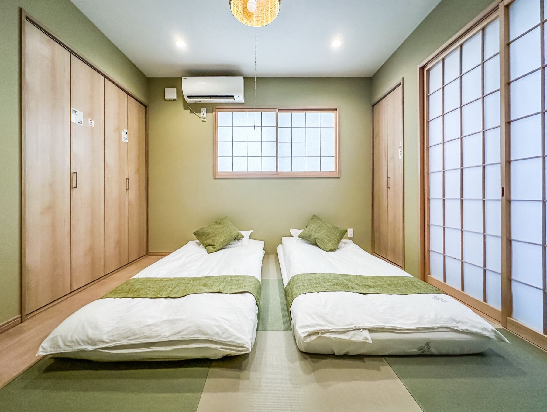 A room with two beds, a window, and a sliding door.