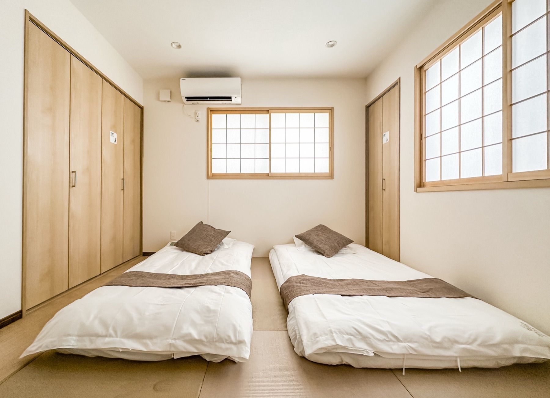 Een kamer met twee bedden, een raam en een airconditioning.