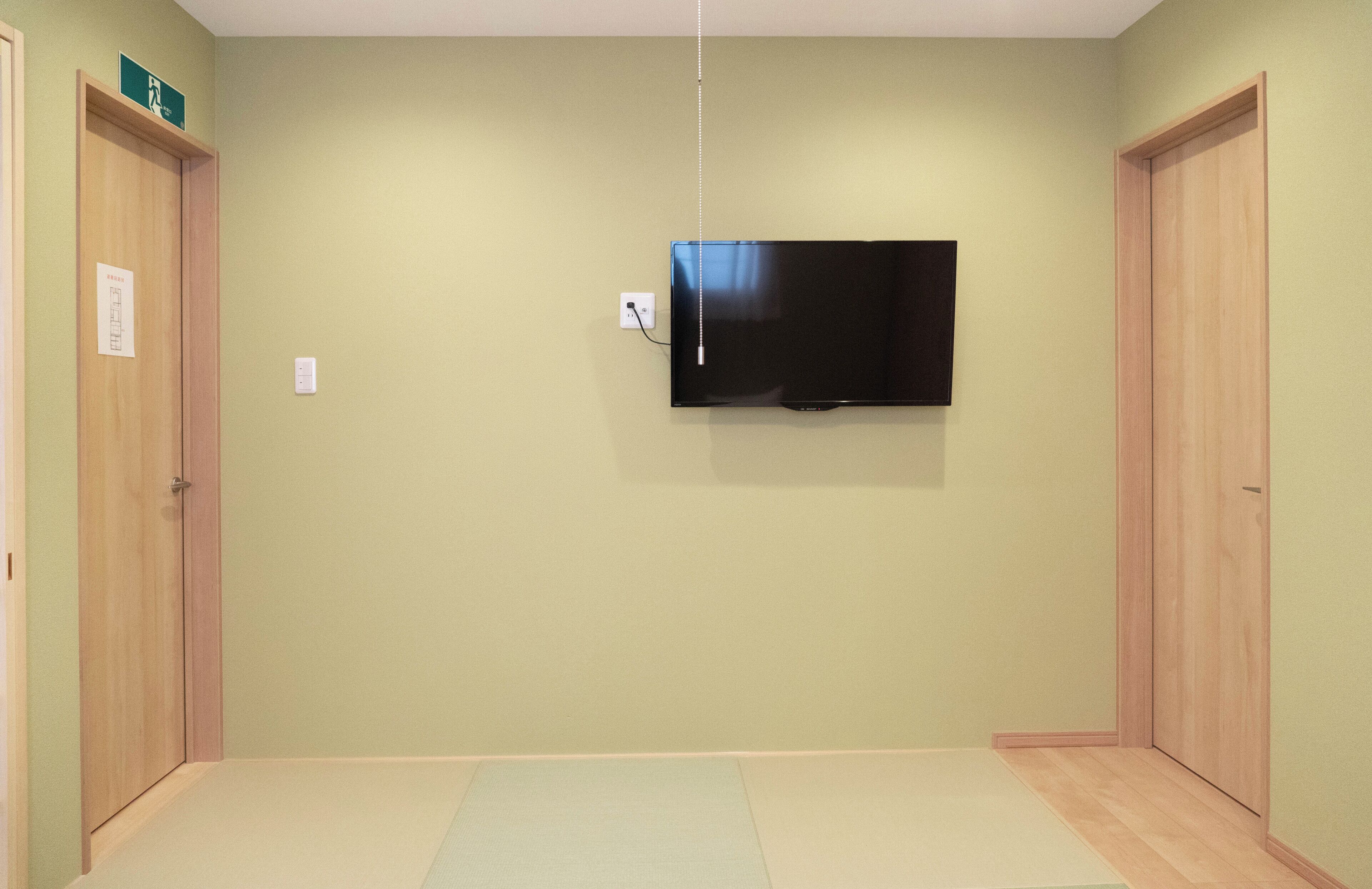 Habitación con televisión de pantalla plana en la pared, puertas de madera y alfombra de color claro.