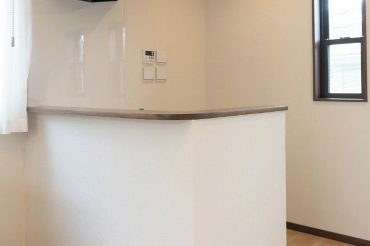 Una esquina de una habitación con pared blanca, una puerta y una ventana.