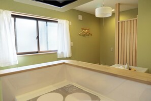 Un baño con una bañera, un ventanal con cortinas, un perchero y un panel de madera.