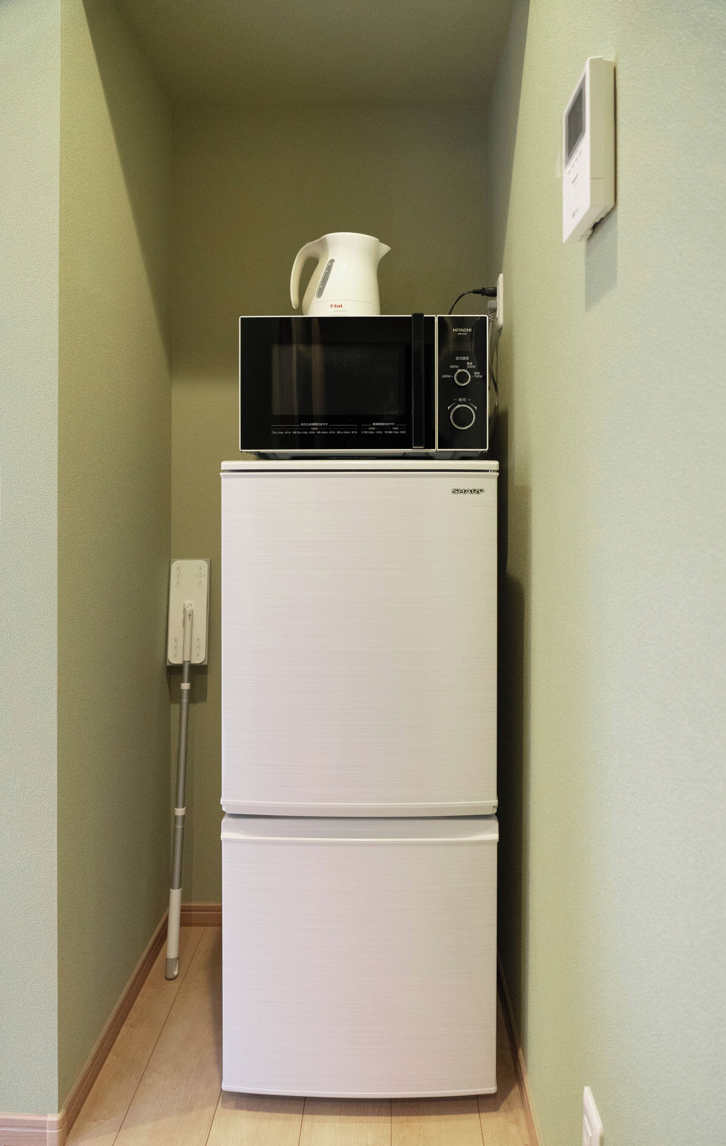 A compact kitchen with a white refrigerator and a black microwave on top.
