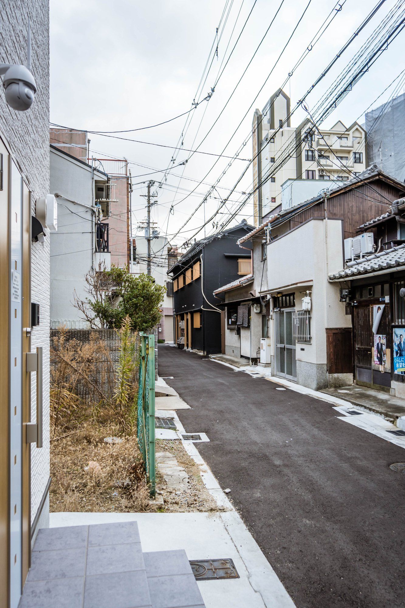 A narrow urban street with buildings on both sides, power lines overhead, and a clear sky.