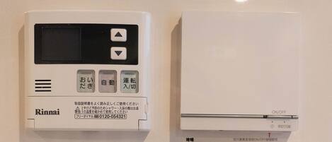Vier bedieningselementen voor de thermostaat met Japanse tekst, waarschijnlijk voor de instelling van de temperatuur.