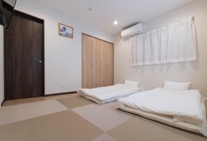 Una habitación con dos camas, un armario de madera, un ventilador de techo y aire acondicionado instalado en la pared.