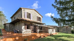 Une maison en pierre avec un porche en bois et des marches menant à une table et des chaises.