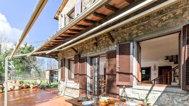 Un bâtiment en pierre doté d’une terrasse en bois et d’une table à manger dressée pour quatre personnes.