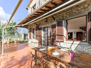Un bâtiment en pierre doté d’une terrasse en bois et d’une table à manger dressée pour quatre personnes.