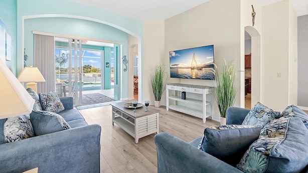 A living room with a TV, sofas, a coffee table, and a view of the outdoors.