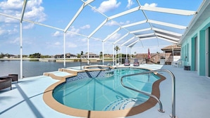 A pool area with a clear view of the water, a covered seating area, and a view of the surrounding landscape.