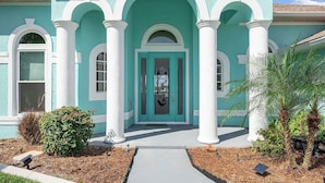 A turquoise house with white columns and a central door.