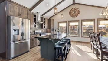 A spacious kitchen with a large island, stainless steel appliances, and a view through the windows.