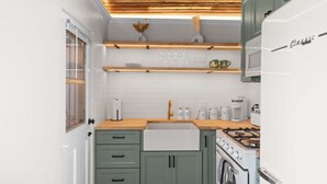 A kitchen with a wooden ceiling, white cabinets, a sink, and a stove.