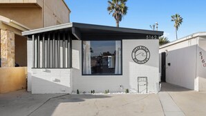 A modern building with a white facade, a large window, and a circular logo on the wall.