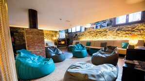 A cozy living room with a stone wall, a fireplace, and comfortable seating including bean bags and a sofa. - Mountain house - Mountain Hostel Tarter (El Tarter)