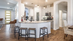 A modern kitchen with a central island, bar stools, and a dining area with a chair.