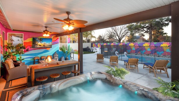 A hot tub area with seating and a bar, surrounded by colorful murals and outdoor furniture.