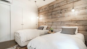 A bedroom with two beds, a ceiling fan, and a wooden wall. - Aquabelle One on Rye Beach (Rye)