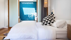 A modern hotel room with a bed, a bedside table, a lamp, and a view of the outside through a glass door. - Aquabelle Four on Rye Beach (Rye)