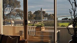 A balcony with a view of the sea and trees. There is a chair and a potted plant on the balcony. - Aquabelle Four on Rye Beach (Rye)