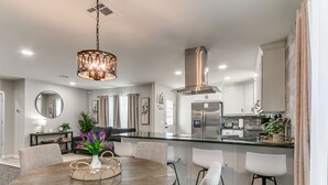 Una cocina moderna con una isla central, electrodomésticos de acero inoxidable y una lámpara colgante.