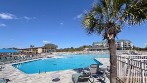 A swimming pool area with lounge chairs and a palm tree. - Modern & Sleek condo Beachfront Resort HHI for 6, private balcony & beach access (Hilton Head Island)