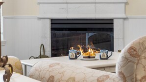 Una chimenea con repisa, dos tazas decorativas y un plato con dos cupcakes.
