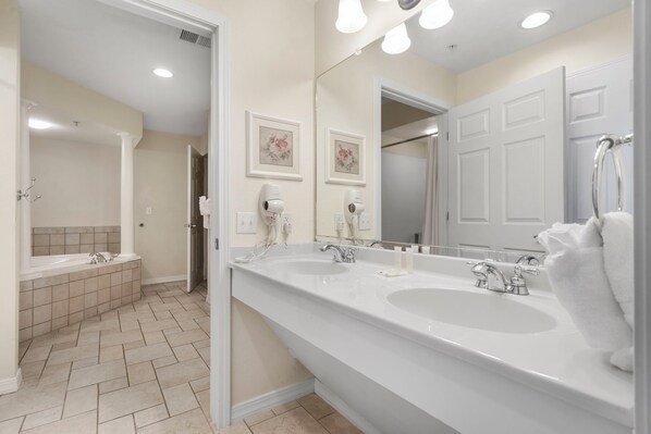 Une salle de bain avec deux lavabos, une baignoire et un grand miroir.