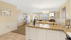 A spacious kitchen with a large island, white cabinetry, and a dining area with a sofa and chairs. - Roomy Condo with Tranquil Views, Lake Access, Outdoor Pool & Free Attraction Tickets (Kimberling City)