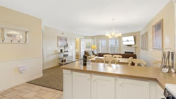 A spacious kitchen with a central island, a dining area with chairs, and a living room with a sofa.