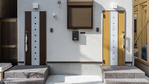 A building facade with two elevator doors, a small window, and a security camera. - HANASTAY OKA (Osaka)