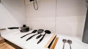 A kitchen counter with various utensils and cookware, including a pot, spatulas, a ladle, chopsticks, and spoons. - HANASTAY OKA (Osaka)