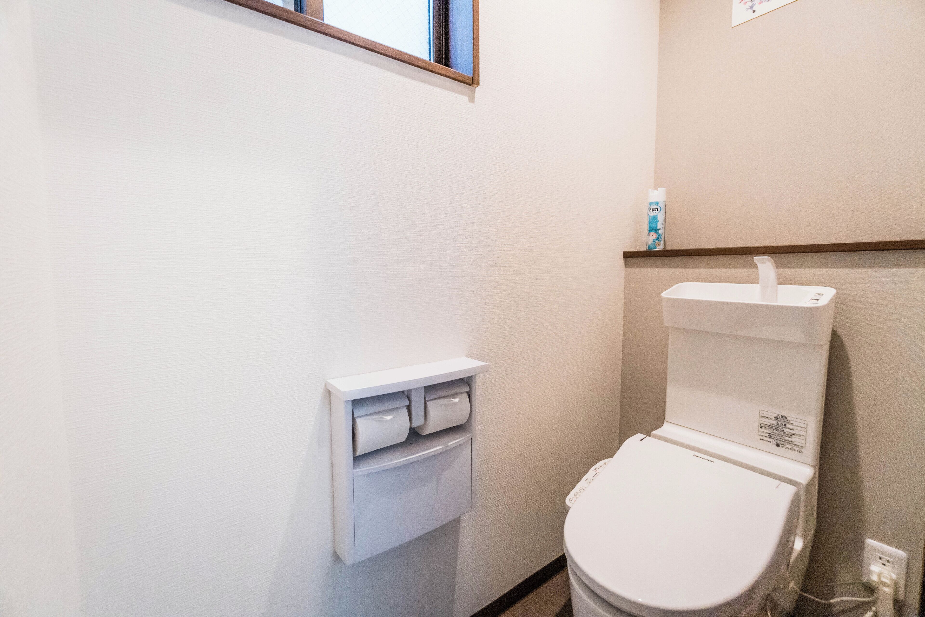 A small, clean bathroom with a toilet, a paper towel dispenser, and a hand dryer.