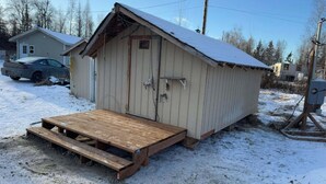 A small wooden shed with a metal door and a ramp leading up to it. - Alaska Native Steam Bath w/Power and Water for RV, free wifi (Wasilla)
