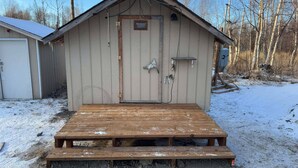 A small wooden shed with a door, a small window, and a wooden bench in front. - Alaska Native Steam Bath w/Power and Water for RV, free wifi (Wasilla)