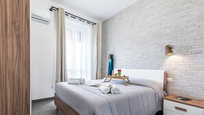 Una camera da letto moderna con un letto, un comodino e una lampada a parete.